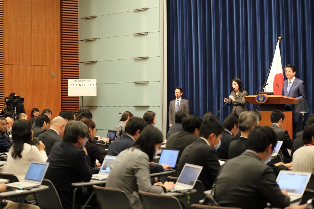 質問するフリーランスの安積明子記者（写真左）。通常司会者は記者の名前を呼ぶが「後段の方の、女性の白いお召し物の方」と指名された