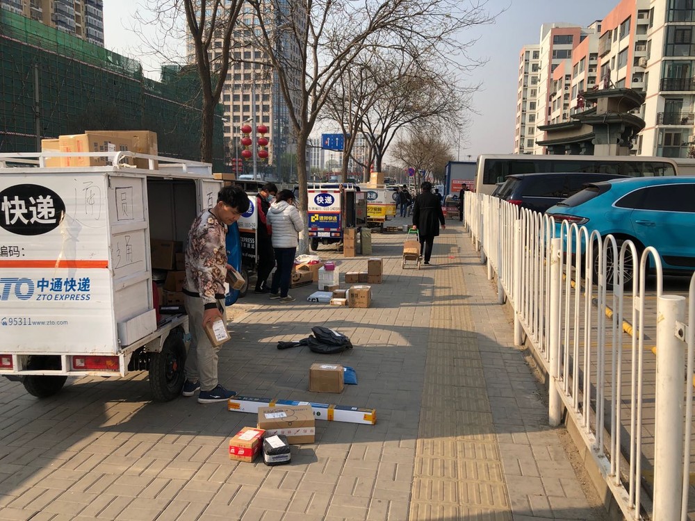 北京の団地の外でずらりと並ぶ宅急便の三輪車。中には入れないため、電話をして取りにきてもらう（2020年4月9日、筆者撮影）