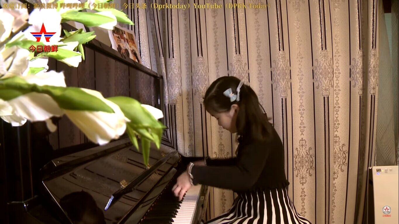 「NEW DPRK」の動画では、7歳の女の子が自宅でピアノを披露する