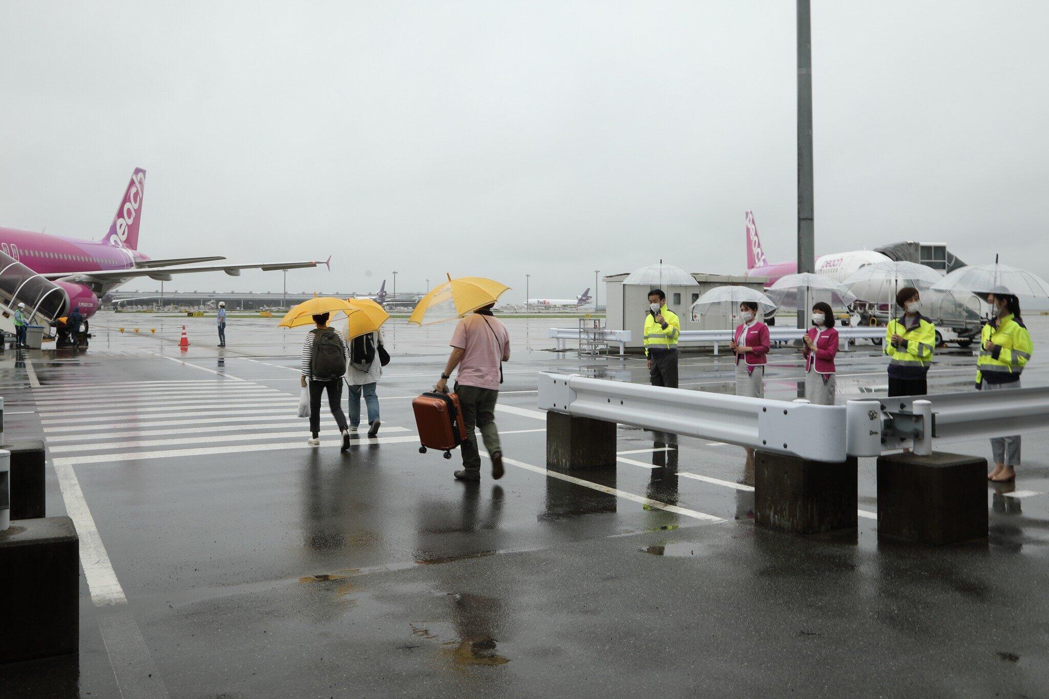 この日の関西空港は雨。客室乗務員らが傘を持って乗客を見送った