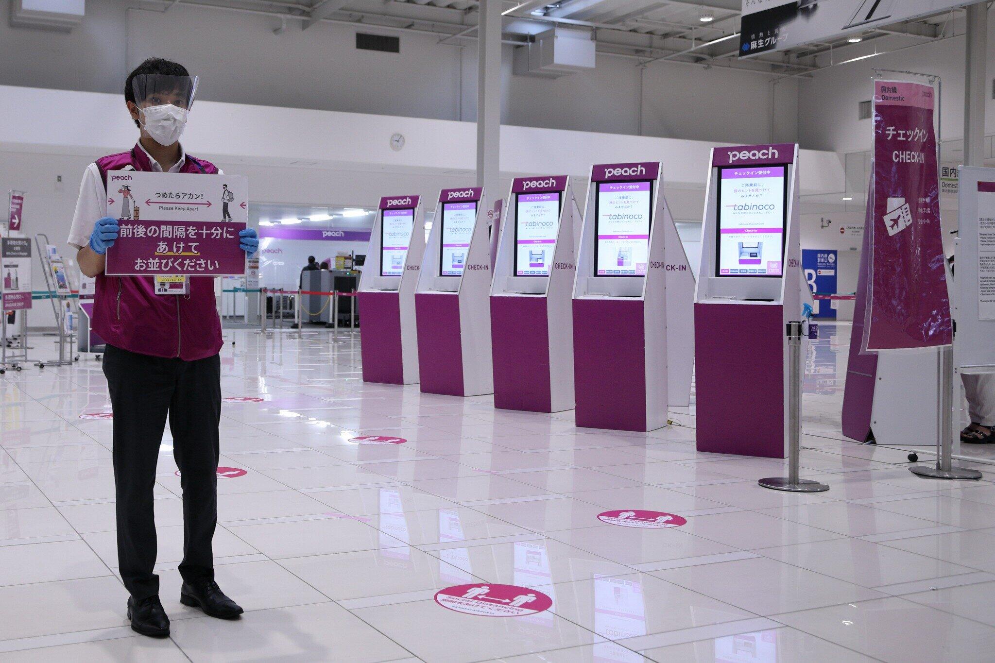 関西空港のチェックイン機では、係員が間隔を開けて並ぶように呼びかけた