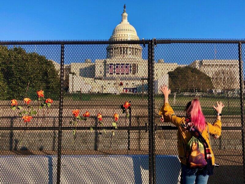 ワシントンにある議事堂前のフェンスに供えられたバラ。その傍らでフェンスにしがみつき、嘆き悲しむ女性（2021年1月、筆者撮影）