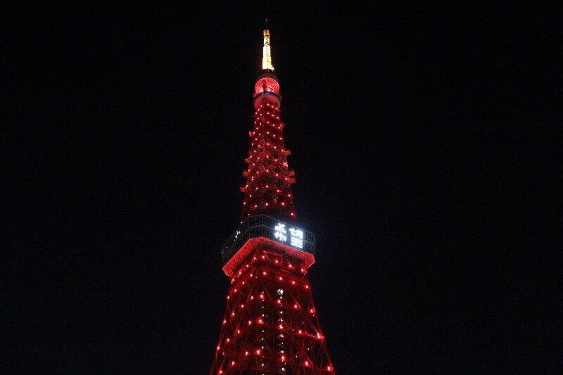 赤くライトアップされた東京タワー。展望台メインデッキの窓にはLEDで「希望」の2文字が投影された