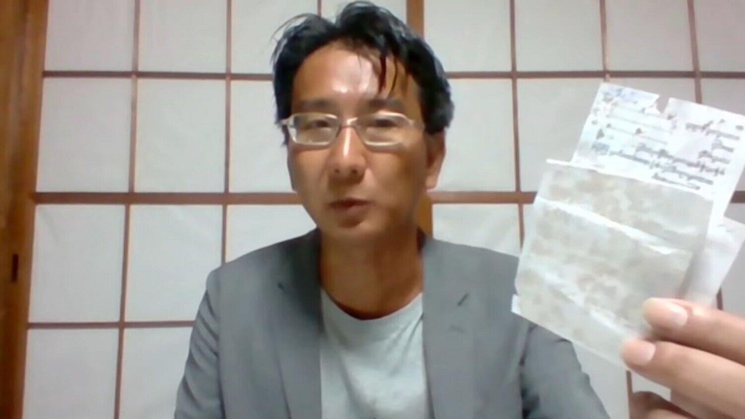 ミャンマーから記憶したフリージャーナリストの北角裕樹さん。拘束中はペンが使えず、コーヒーを使って書いたメモをカメラに向かって示した（写真は日本外国特派員協会の配信動画から）