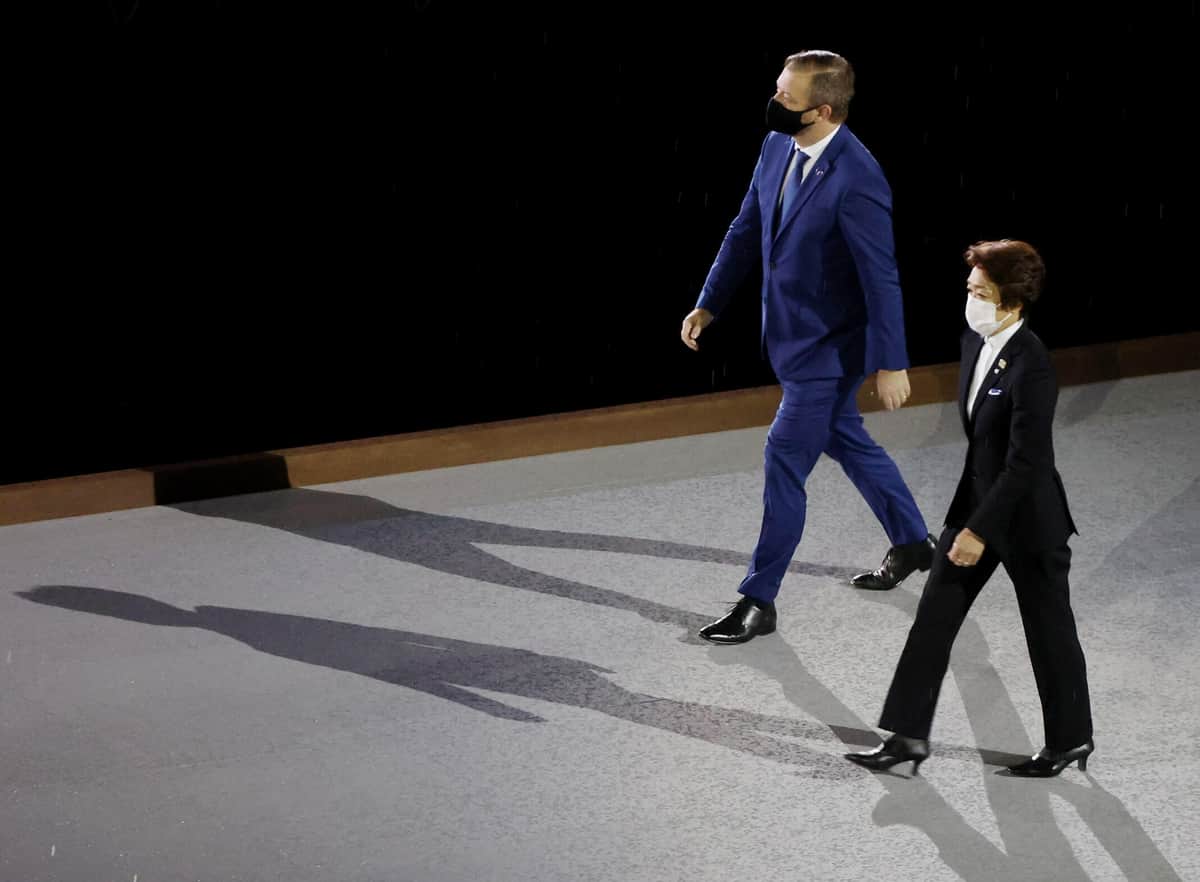 会場に入ってくるパーソンズ氏と橋本氏（写真：ロイター/アフロ）