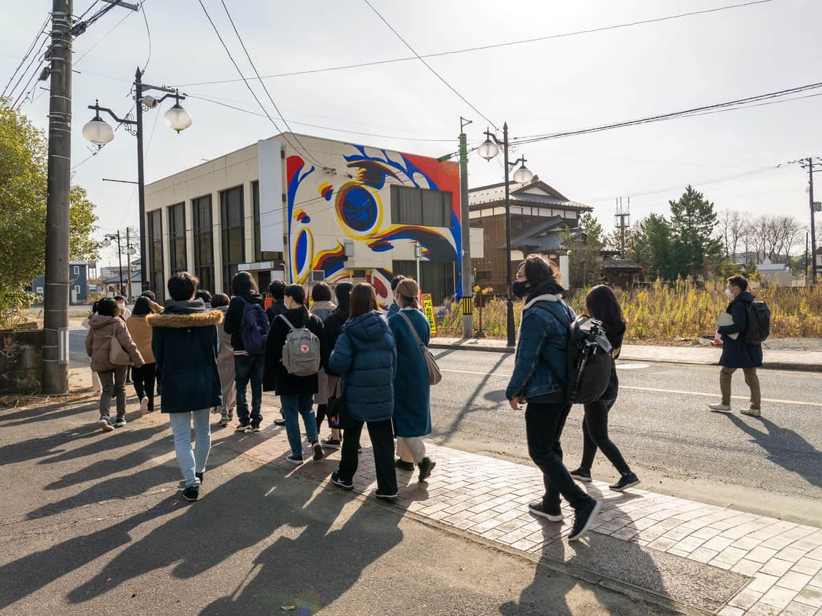 「双葉タウンストーリーツアー」の参加者の前に、大きなダルマが描かれた建物が登場（写真提供：F-ATRAs）