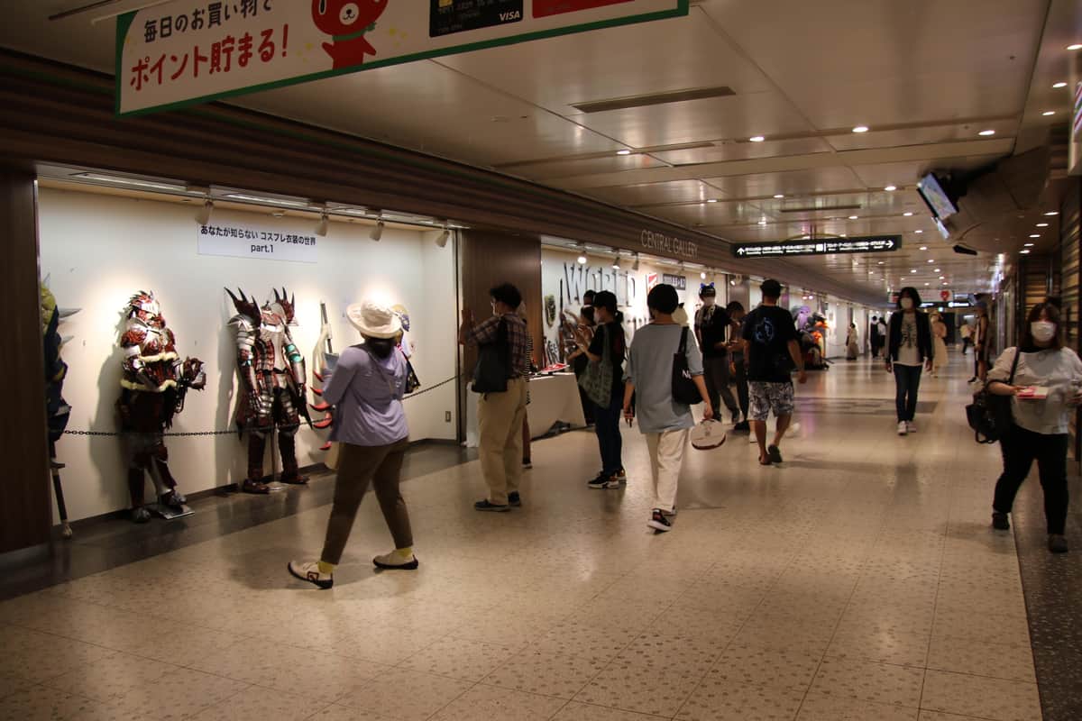 コスプレ衣装や武器の展示を楽しむ人々