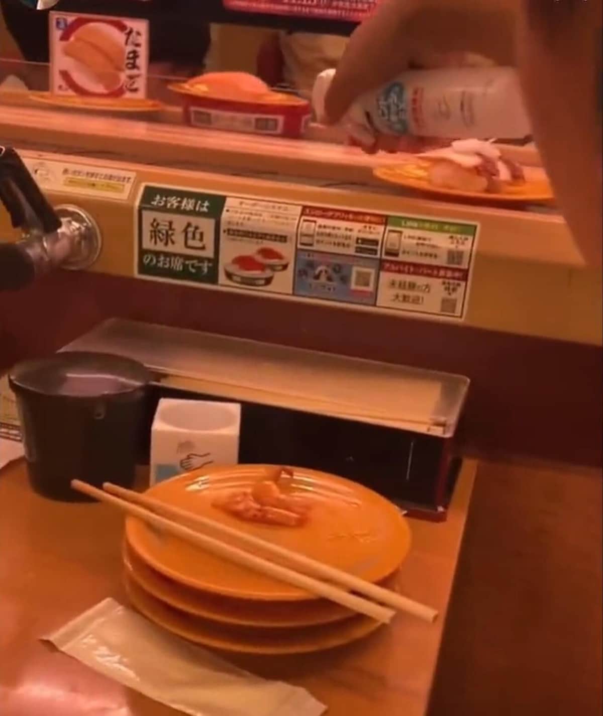 寿司の皿にスプレーを向ける男性（投稿された動画から）