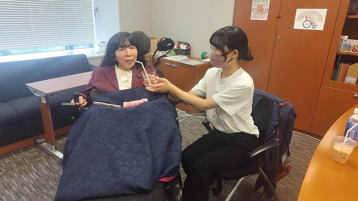 介助者の女性に、ストローで飲み物をいただく木村さん（菅沼栄一郎撮影）