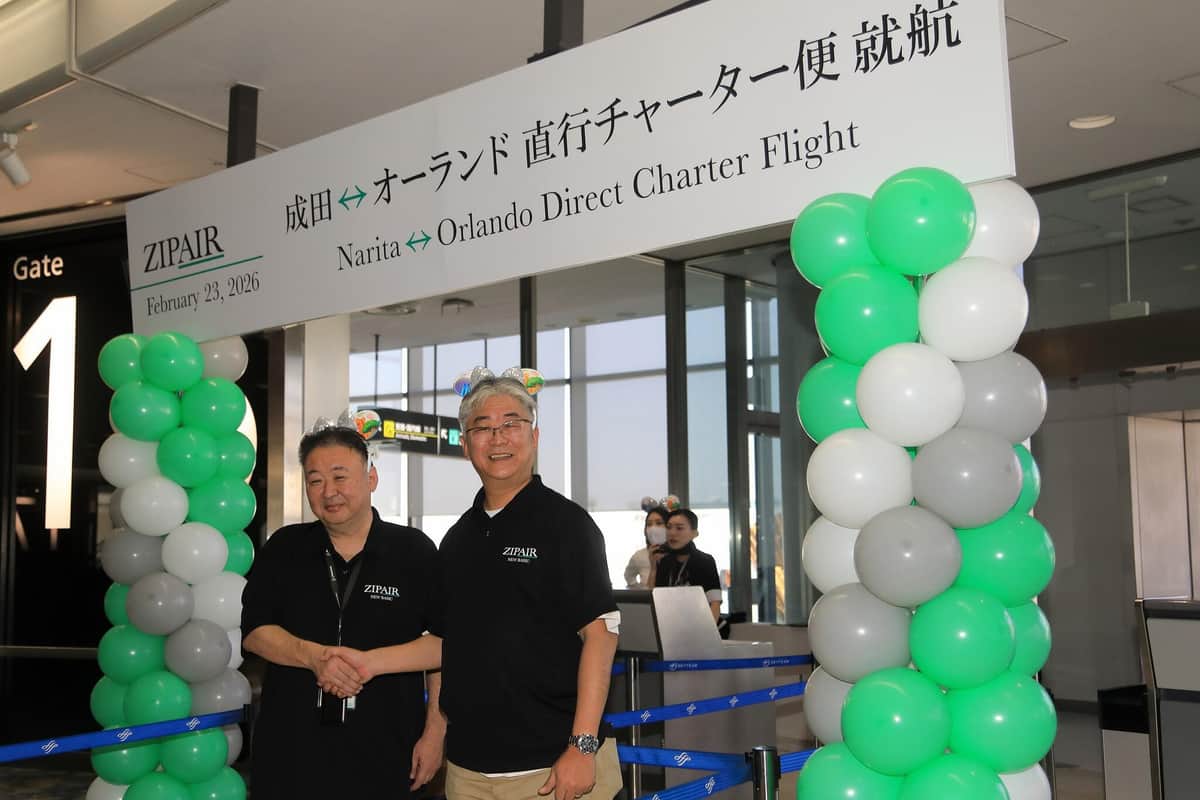 新旧社長はカチューシャをつけて握手。左から取締役事業本部本部長の深田康裕氏、西田真吾社長