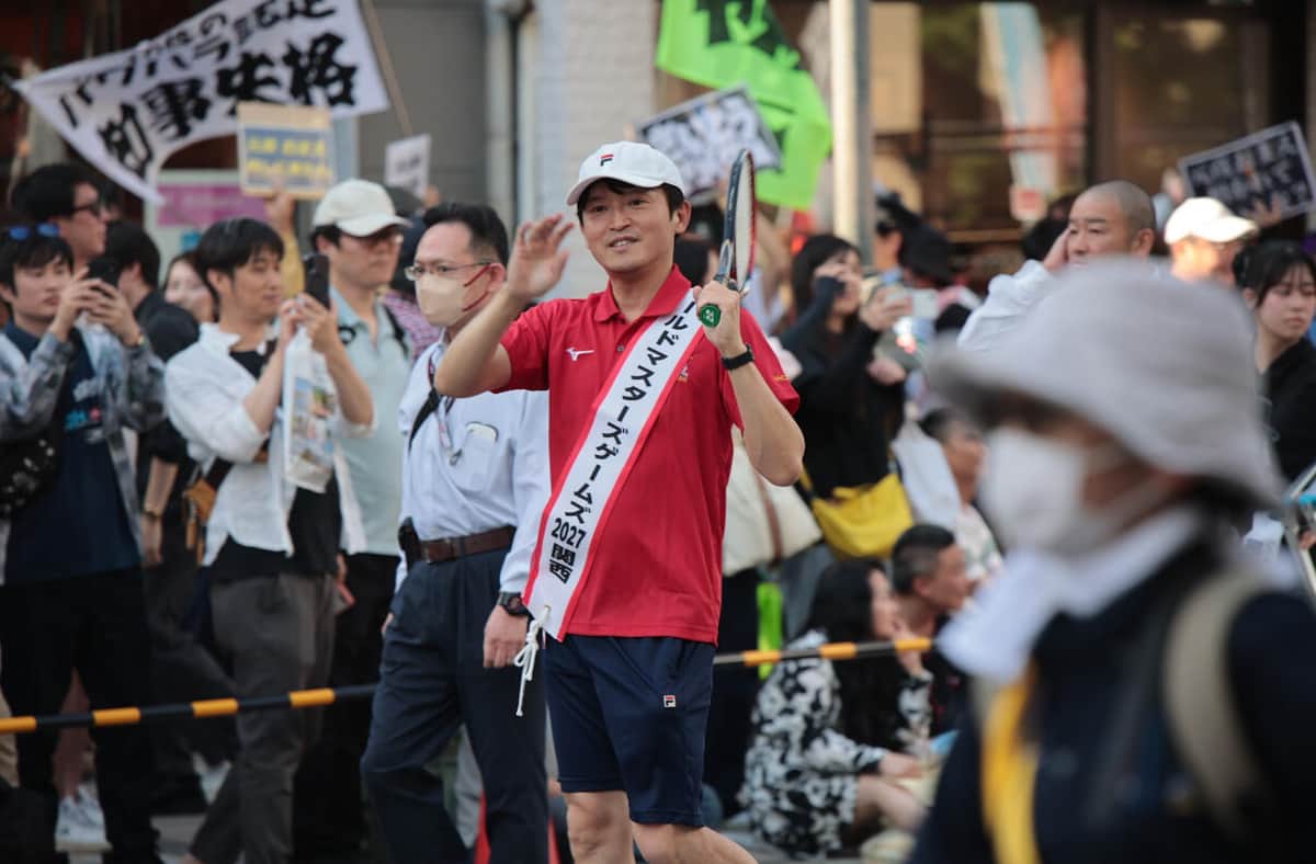斎藤知事が手を振る背後には抗議のプラカードが（5月17日、神戸市中央区）
