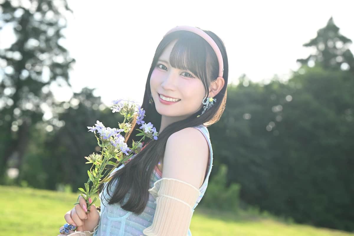 草原で花を手に笑顔を見せる大村杏さん。MVは自然の中で、女の子らしい姿をかわいく描いた　（c）2026 SKE, Inc. / AMC