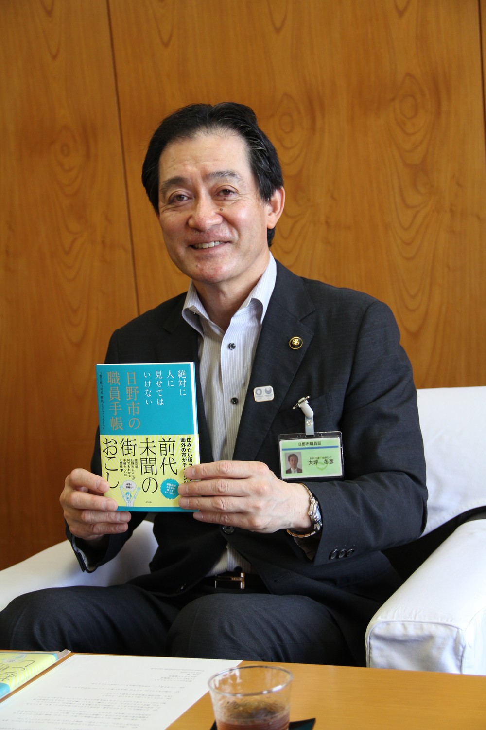 「職員手帳」を手に、「日野市のいいところを発信していく」と話す大坪市長