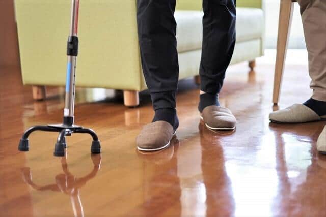 四脚杖で歩く高齢者と介助する人（写真はイメージ）