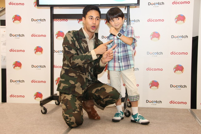 「ドコッチ」をつけた男の子とポーズをとるユージさん