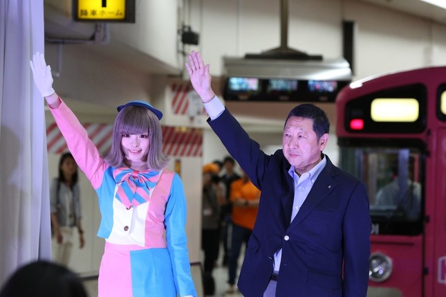 一番列車のセレモニーで右腕を上げる、きゃりーさんと西武鉄道の後藤高志取締役会長