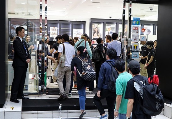 小雨が降り出す中、辛抱強く待ち続けた客を歓迎する表参道店のスタッフ