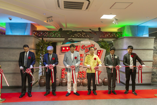 オープニングセレモニーのテープカット。右からパフォーミングアーティストCYRIL(セロ)氏、株式会社シュガートレイン代表取締役井手裕一氏、沖縄県文化観光スポーツ部部長嘉手苅孝夫氏、トランスコスモス株式会社代表取締役社長兼COOの奥田昌孝氏、吉本興業共同代表取締役社長CEOの大崎洋氏、株式会社SNK代表取締役社長外山公一氏