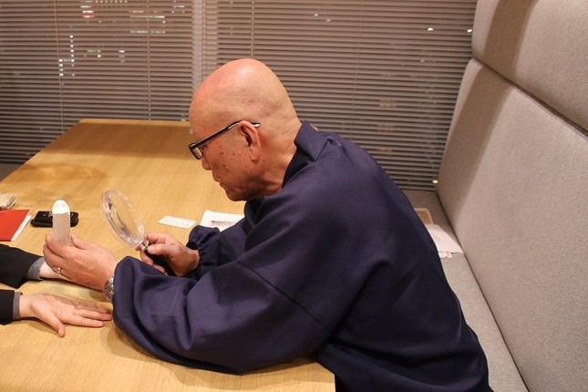 虫眼鏡やライトを使い、記者の目や手指を見て鑑定