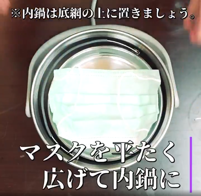 「電鍋」の蓋を開け、マスクを平たく広げて内鍋に入れる