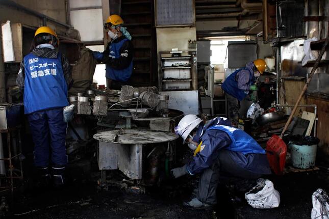 東日本大震災で被災した石巻市で、清掃活動にあたるボランティア。2011年4月16日撮影（写真：AP/アフロ）