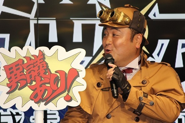 ゲームの決め台詞「異議あり！」のパネルを持つ山崎さん