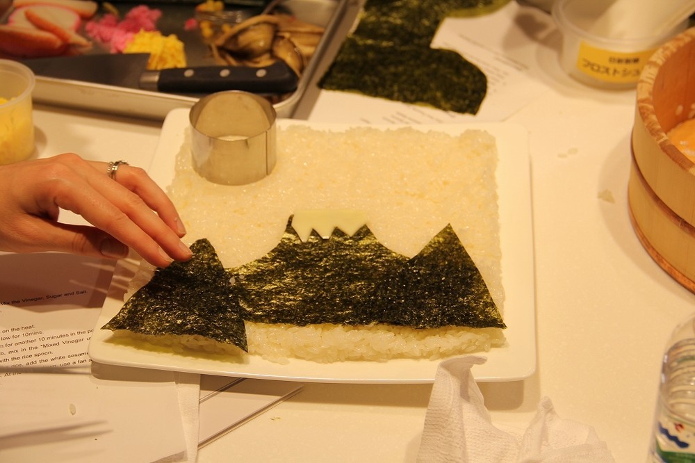調理途中のちらし寿司1　酢飯を広げ、焼き海苔を敷いて富士山を絵画のように表現