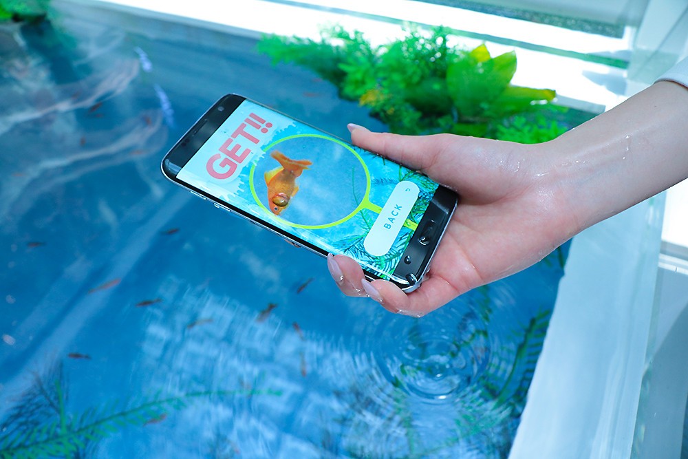 水槽の中にGalaxy S7 edgeを突っ込み、バーチャル金魚をすくえるアプリの体験コーナーも