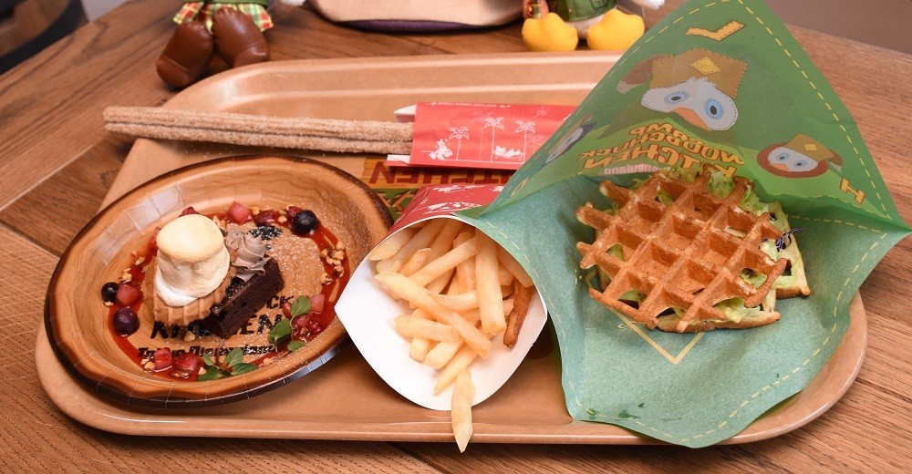 「キャンプ・ウッドチャック・キッチン」で提供される新メニュー。左から「スモア風チョコレートブラウニー」(400円)、「フレンチフライポテト」(220円)、「ワッフルサンド(スパイシーシュリンプ＆アボカド)」(700円)。ワッフルサンドはほかに「フライドチキン、メイプルソース付き」と「ベーコン、ベジタブルBBQソース」を用意