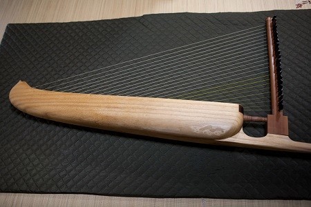 箜篌の腕木を床に横たえると、こんな感じになる。腕木の部分は、黒柿と花梨でできている。野原さんが信頼する、下町の古老の職人が作った。