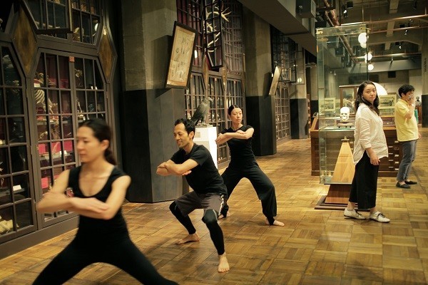 右端の黄色のシャツの男性が演出家の金世一氏。標本の間を練り歩く役者たちの動きを見守る。脚本を練りながら、10月から制作に入る。