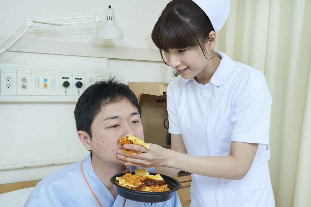 「患者に手づかみでオムライスを食べさせる看護師」