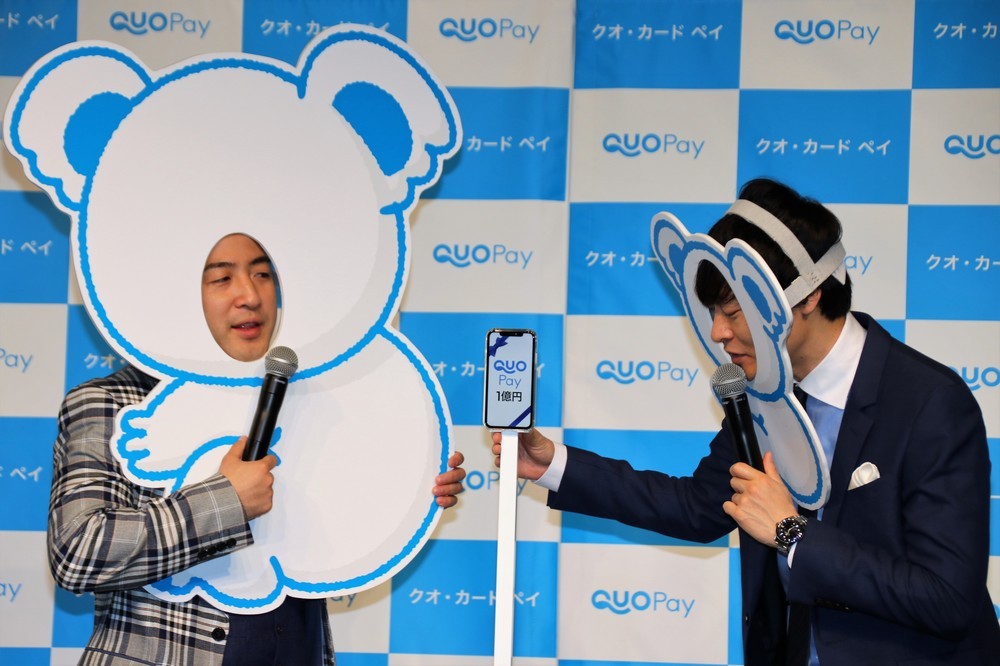 「QUOPay1億円」と画面表示されたスマートフォンが登場