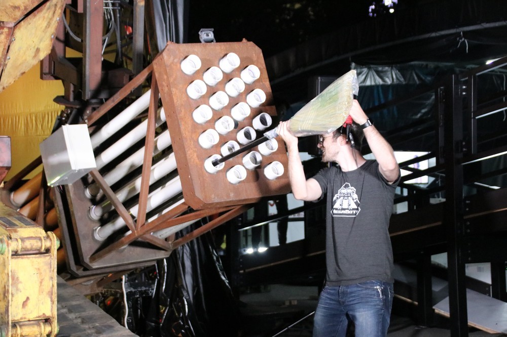 Tシャツ発射の様子を見せるため、左アームの穴に丸めたTシャツをほうきで押し込むマットさん