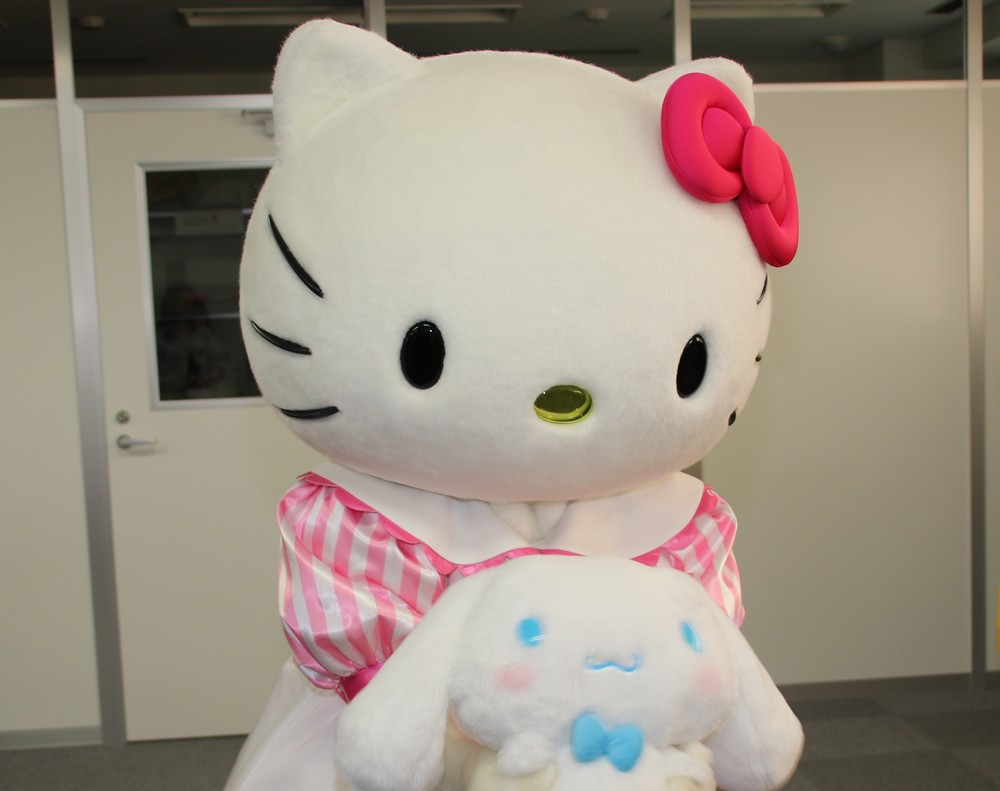 シナモンぬいぐるみに編集部内の様子を見せてあげるキティ