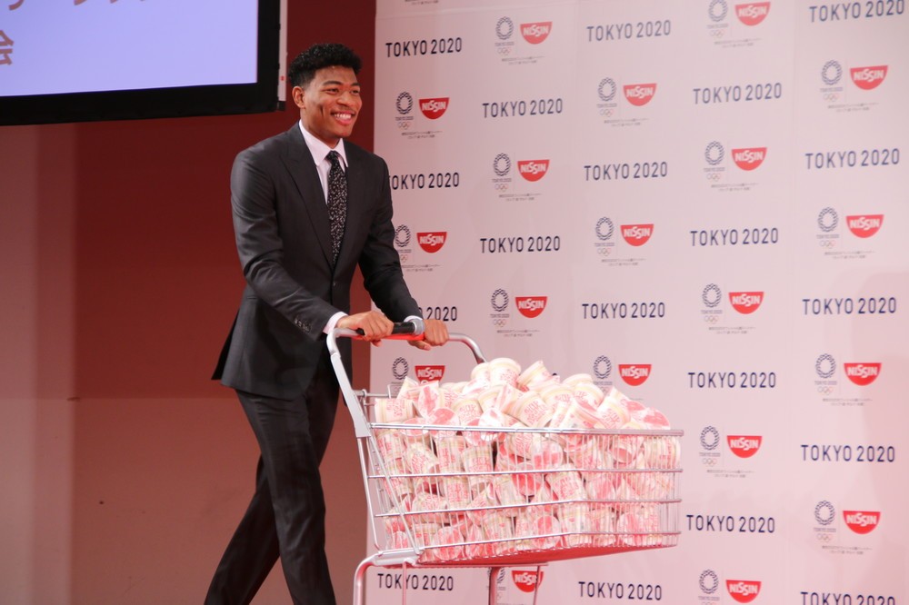 カップヌードルが大量に入ったカートを笑顔で運ぶ八村選手