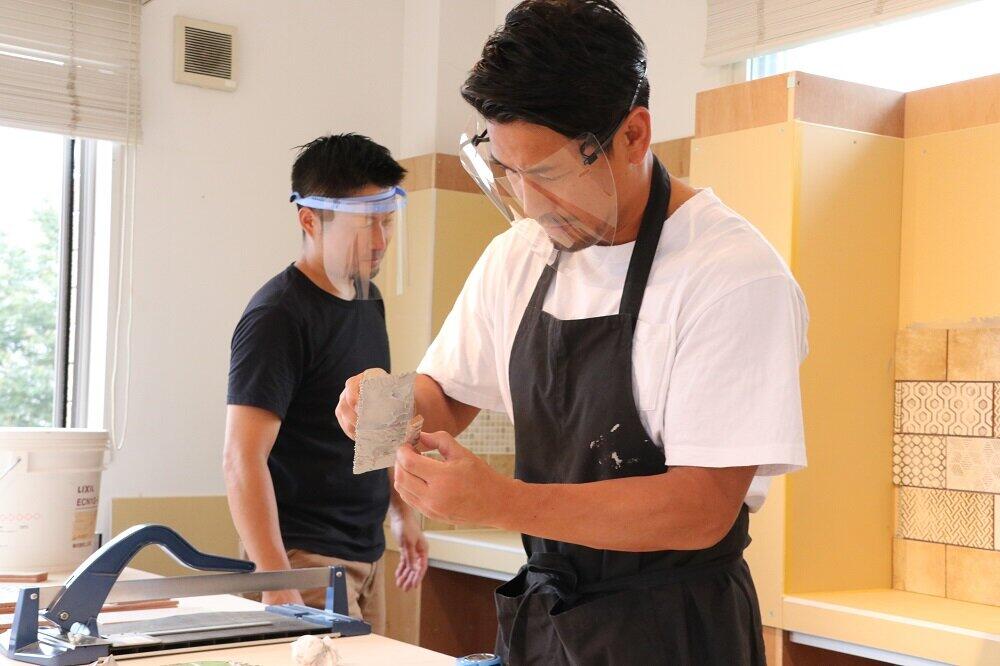 タイルの裏側にセメントを塗り付ける魔裟斗さん