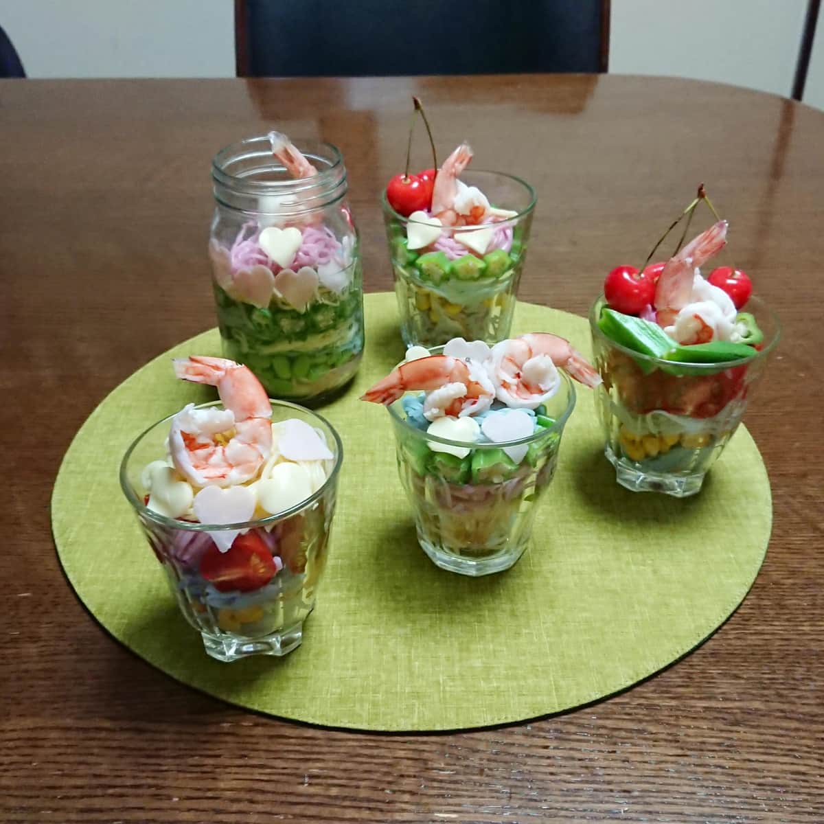 ミニトマト、スイートコーン、さっと茹でたオクラ、ゆで海老などと一緒にコップに入れて、パフェをイメージして盛り付けた。ハムとスライスチーズはクッキー型でハートに抜いた。