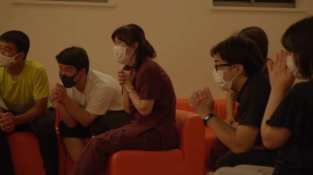 誰かを信じて声援を送る人々の姿を描く